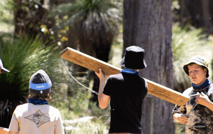 A group of boys doing a team building challenge holding a large plank of wood