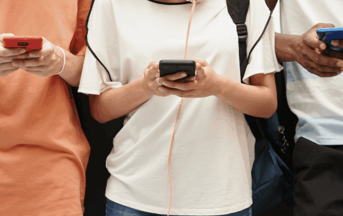 Three young people staring at their phone screens.