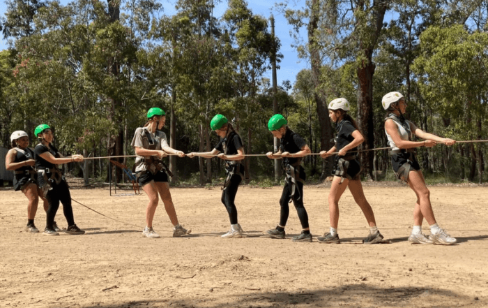 Students working together, holding a rope, to solve a challenge